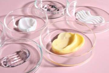Different cosmetic products in Petri dishes on pink background, closeup