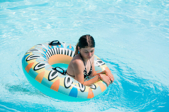 Beautiful young girl playing in a tropical pool with her inflatable ring