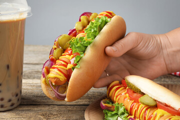 Woman with tasty hot dogs and bubble tea at wooden table, closeup