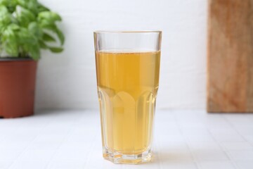 Glass with dirty water on white tiled table, closeup