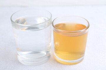 Glasses with clean and dirty water on light table, closeup