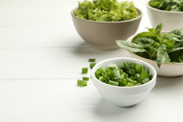 Different aromatic herbs in bowls on white wooden table, closeup. Space for text