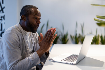 African American man participating in video call on laptop at office desk