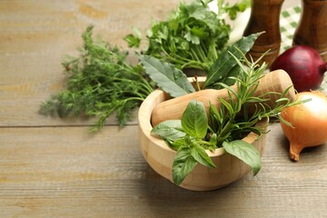 Different aromatic herbs in mortar on wooden table, closeup