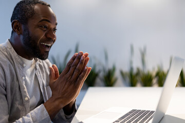 African American man participating in video call on laptop at office desk