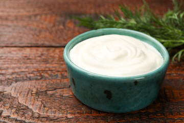 Tasty sour cream with dill on wooden table, closeup. Space for text