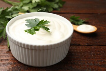 Tasty sour cream with parsley on wooden table, closeup