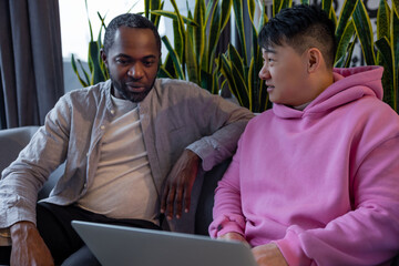Multiethnic business partners collaborating on laptop in informal workspace