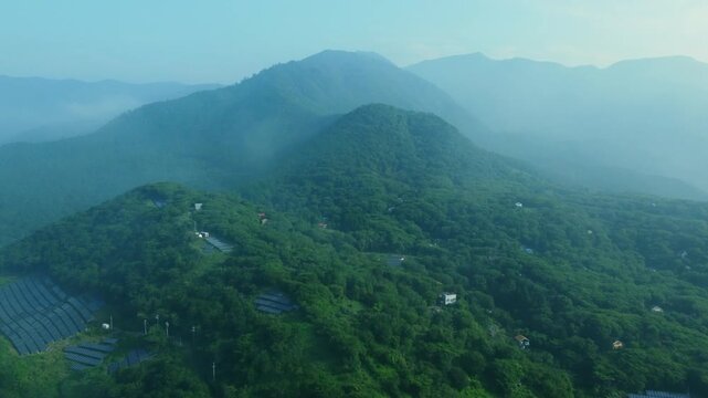 明朝に霧がかった山の中にある家々を空撮 