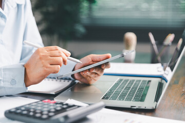 Office businesswoman hand to operate calculator analyzing financial data, counting costs on desk. accounting, financial analysis for business budget planning, calculation support, finance management.