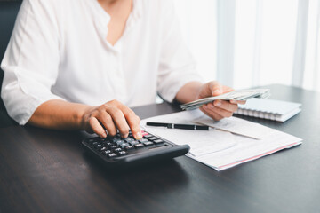 Using calculating machine, household carefully manages each bill and expense to plan financial...