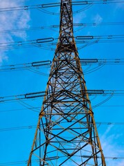 This transmission tower stands tall against a backdrop of blue skies and fluffy clouds, showcasing...