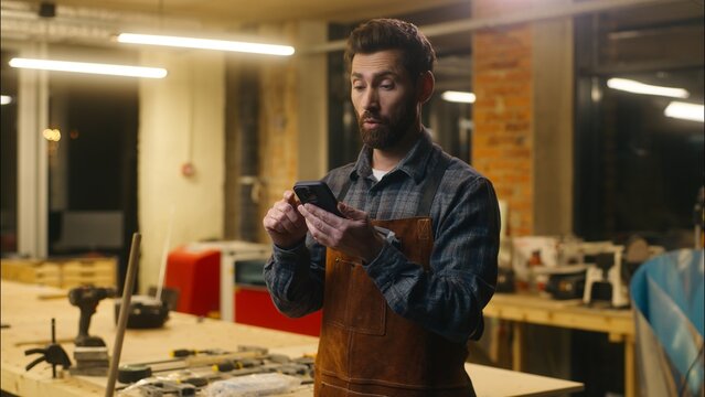 Happy Caucasian man showing green screen display in workshop wood master guy artist male repairman using mobile phone architect user recommending application chromakey carpenter thumb up advertisement