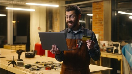 Happy Caucasian employer male repairman guy hold laptop carpenter use credit card remote shopping...