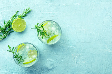 Gin tonic, overhead flat lay shot with rosemary and lime. Fresh summer cocktail with ice, with copy space