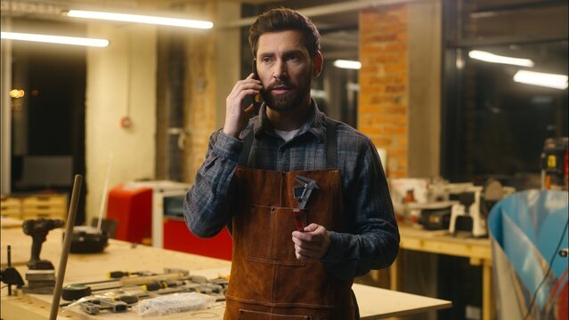 Professional Caucasian artist craftsman male wood master man architect builder talking mobile phone worker guy negotiation with client in workshop carpenter cellphone call repairman joiner discussing