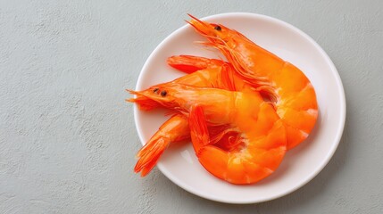 Fresh shrimp with tail curled placed on a simple plate over clean textured background