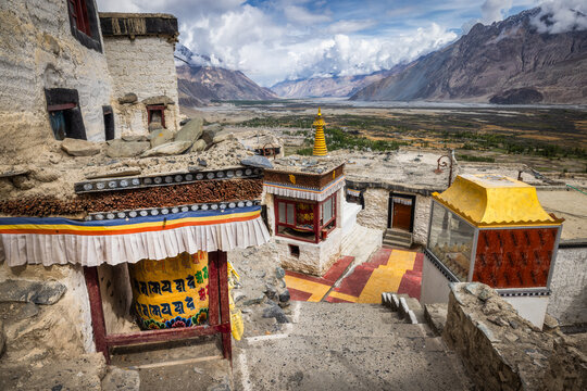 View of ancient monastery architecture blending with the stark, mountainous landscape under a dramatic sky, Diskit Monastery, Ladakh Division, India.