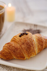 Delicious croissant. Freshly baked croissant on a plate beside a cup of coffee. Creating a warm and inviting breakfast scene. Selective focus.