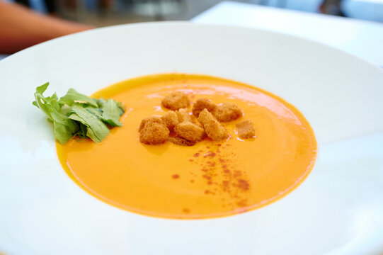 creamy vegetable soup made from carrots, pumpkin, and more, garnished with paprika and croutons, served as a warm starter