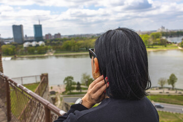 A Latin girl gazes over a cityscape and river from a high viewpoint. Selective focus