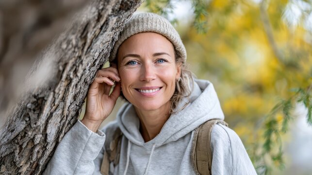 Smiling woman in a cozy sweater enjoys nature in vibrant autumn foliage - Powered by Adobe