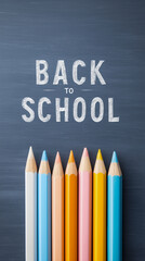 Back to School text written in chalk on a blackboard. A top-down flat lay with a row of colorful pencils. A classic, creative background for education, art, and school supplies.