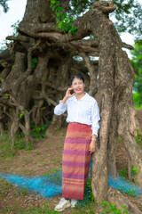 Asian women in traditional poses.Laos girl in traditional dress against a backdrop of trees.