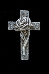 Stone cross with carved rose, symbol of remembrance and sorrow.