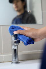 housekeeper is cleaning the faucet in the bathroom.
