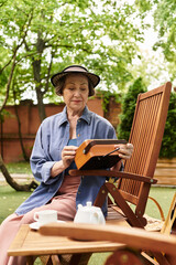 Beautiful senior woman enjoys quiet moments in her garden while painting and reflecting on life