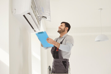 Happy worker handyman man checking, installing attaching wall air conditioning unit, AC repair,...