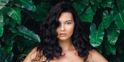 Confident Brunette Woman with Voluminous Curly Hair Posing in Tropical Setting