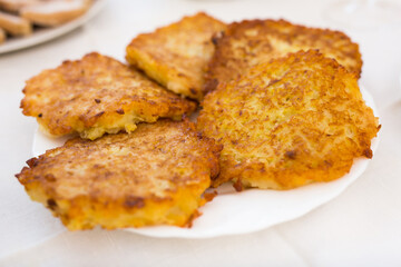 Potato pancakes with sour cream on white plate