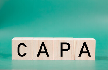 Word capa. Wooden small cubes with letters isolated on green background with copy space available