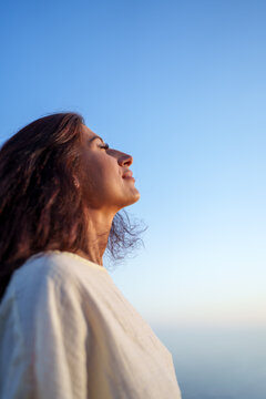 Young woman breathing fresh air and enjoying freedom under blue sky, mindfulness and wellbeing concept