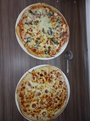 Two homemade pizzas on wooden table. Top view of two delicious homemade pizzas with cheese and toppings on wooden table, perfect for food, cooking, and Italian cuisine concepts.