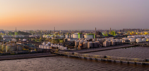 Aerial view of a large coastal oil refinery with storage tanks at dusk