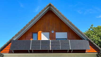 Modern house features solar panels under a clear blue sky with wooden accents on the façade