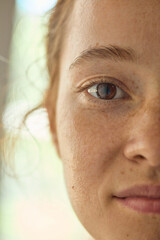 Extreme close-up of freckled woman eye and skin texture with calm natural expression. Concept of...