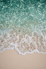 Overhead capture of sparkling sea foam meeting beige coastline in calm light, ideal for nature backdrops and tropical holiday design