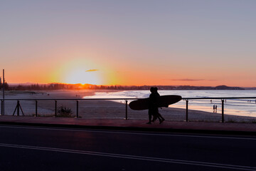 Surfers silhouette against Coolangatta beach sunset. Gold Coast, Australia