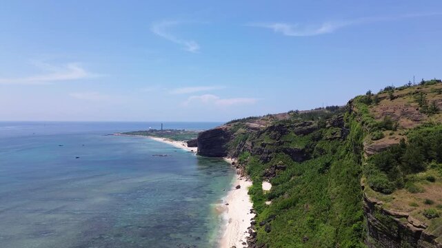 Ascending aerial showing coastal cliffs, beach and volcanic terrain of Ly Son Island under clear daylight.