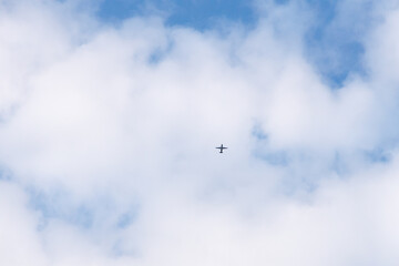 Airplane flying through the sky in far distance passing through the clouds