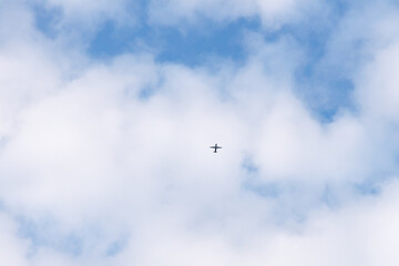 Fototapeta premium Airplane flying through the sky in far distance passing through the clouds