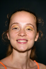 Studio beauty portrait of joyful woman with golden eyeshadow and wide smile. Concept of glowing...