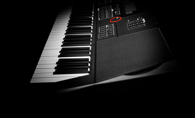 Closeup of a modern digital piano keyboard with black and white keys in a diagonal perspective on a dark background.