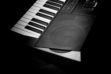 Closeup of a modern digital piano keyboard with black and white keys in a diagonal perspective on a dark background.