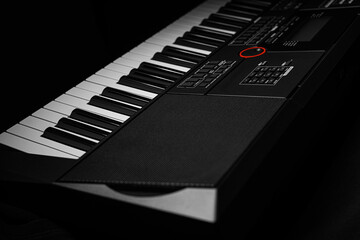 Closeup of a modern digital piano keyboard with black and white keys in a diagonal perspective on a dark background.