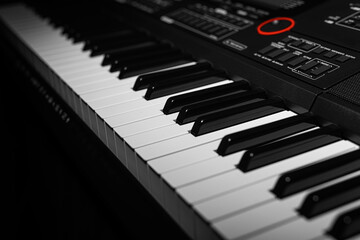 Closeup of a modern digital piano keyboard with black and white keys in a diagonal perspective on a dark background.